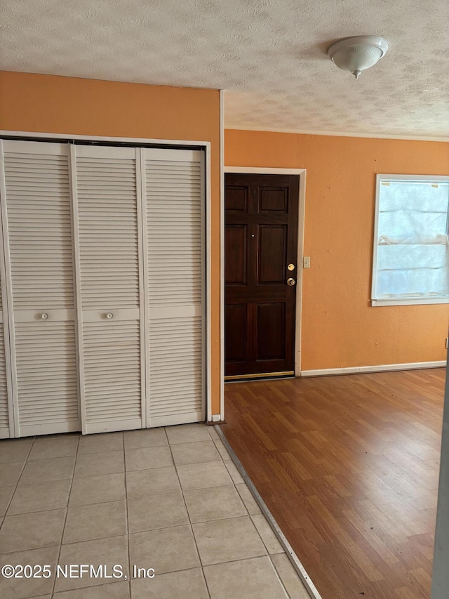 foyer entrance with a textured ceiling and light tile patterned flooring