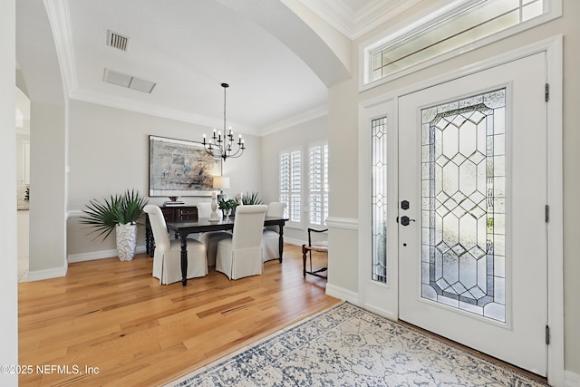 foyer entrance featuring crown molding, wood-type flooring, and an inviting chandelier