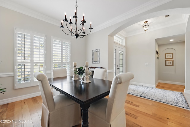 dining space featuring hardwood / wood-style flooring, ornamental molding, and a notable chandelier