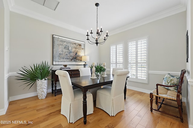 dining room with a notable chandelier, crown molding, and light hardwood / wood-style flooring