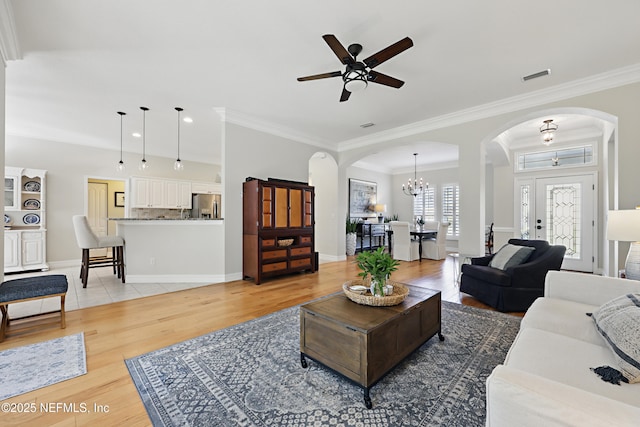 living room with ornamental molding, ceiling fan with notable chandelier, and light hardwood / wood-style flooring