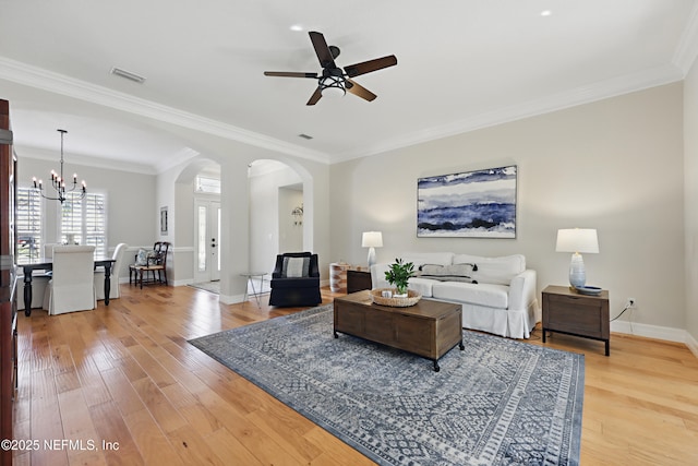 living room featuring ceiling fan with notable chandelier, ornamental molding, and hardwood / wood-style floors