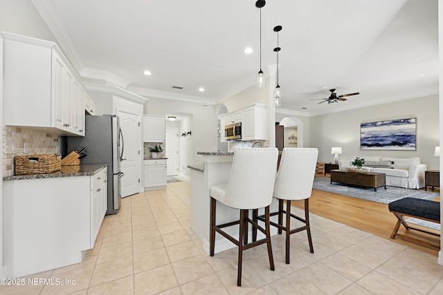 kitchen with white cabinetry, dark stone counters, stainless steel appliances, and light tile patterned flooring