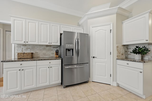 kitchen with white cabinetry, ornamental molding, dark stone counters, and stainless steel fridge with ice dispenser