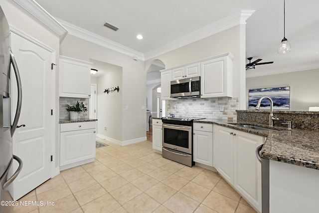 kitchen featuring sink, white cabinetry, stainless steel appliances, decorative light fixtures, and dark stone counters