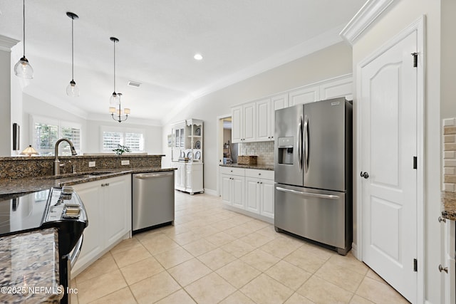 kitchen featuring hanging light fixtures, dark stone countertops, ornamental molding, stainless steel appliances, and white cabinets