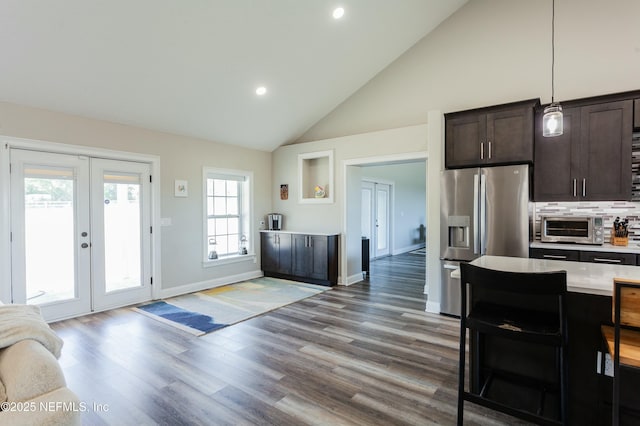 kitchen with pendant lighting, tasteful backsplash, a kitchen bar, stainless steel fridge with ice dispenser, and dark brown cabinets