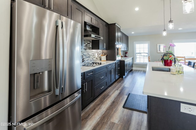 kitchen with appliances with stainless steel finishes, pendant lighting, sink, decorative backsplash, and wall chimney range hood