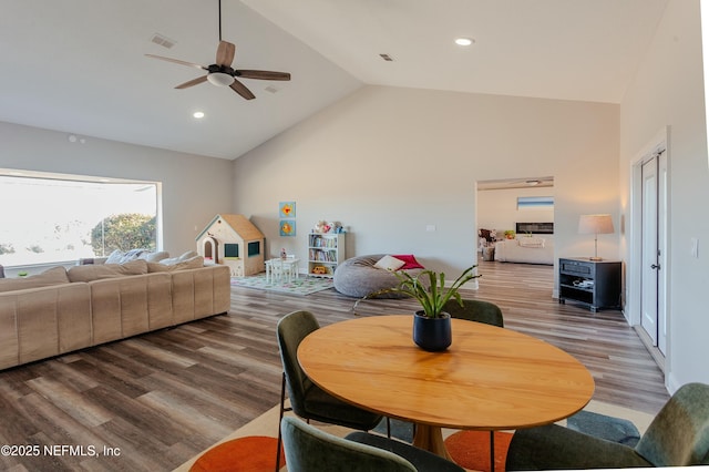 dining room with ceiling fan, wood-type flooring, and high vaulted ceiling