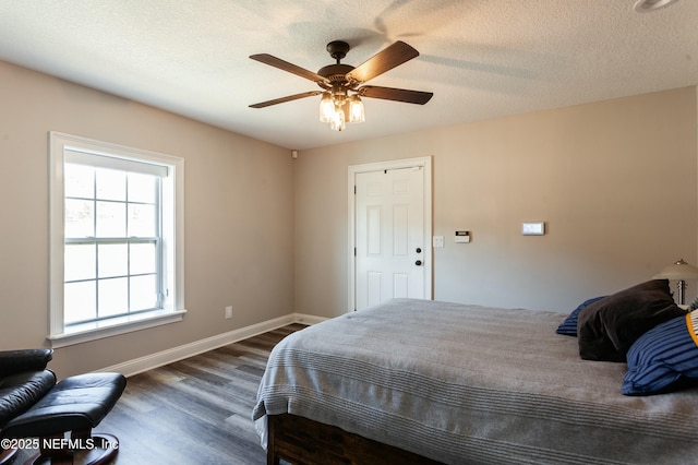 bedroom featuring dark wood-type flooring, a textured ceiling, and ceiling fan