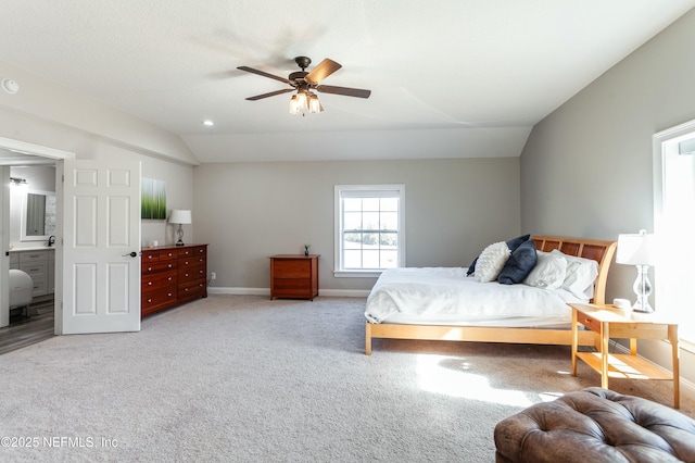 bedroom featuring light carpet, connected bathroom, lofted ceiling, and ceiling fan