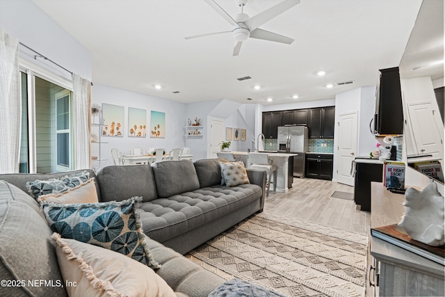 living room with ceiling fan, sink, and light hardwood / wood-style flooring