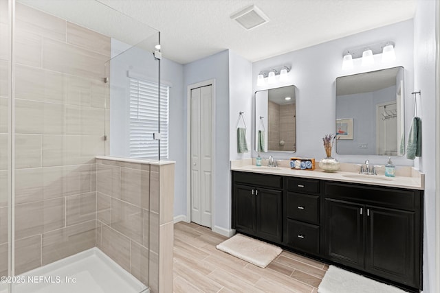 bathroom featuring vanity, a textured ceiling, and a tile shower