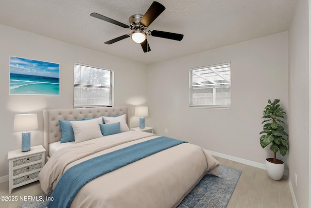 bedroom featuring ceiling fan, light hardwood / wood-style floors, and a textured ceiling