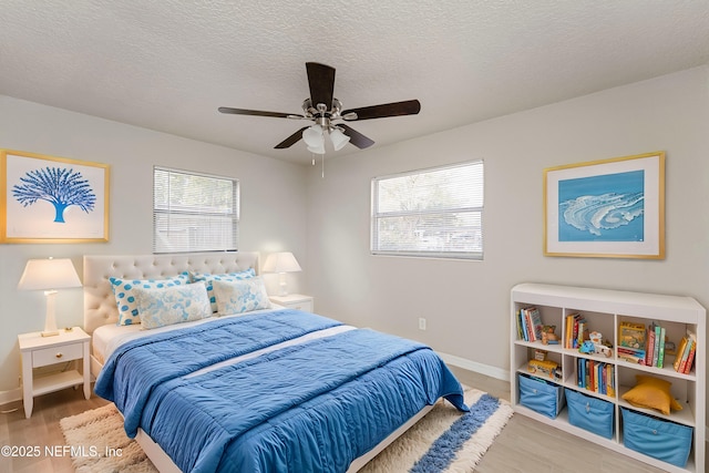 bedroom with multiple windows, wood-type flooring, and a textured ceiling