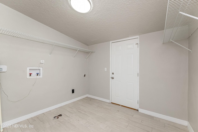 clothes washing area featuring electric dryer hookup, hookup for a washing machine, light hardwood / wood-style flooring, and a textured ceiling