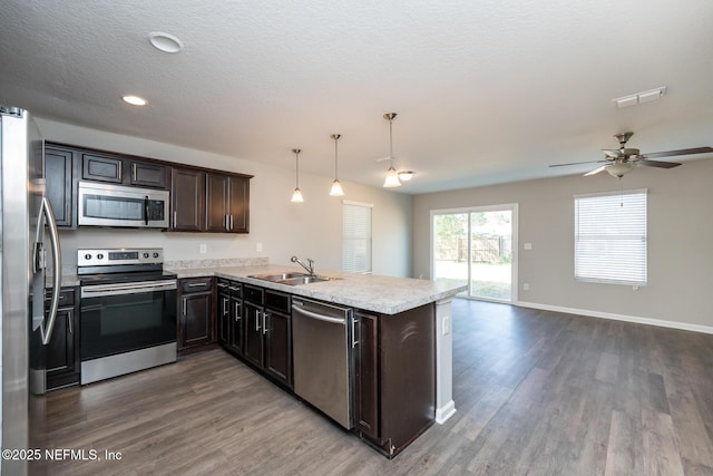 kitchen with hanging light fixtures, appliances with stainless steel finishes, sink, and kitchen peninsula