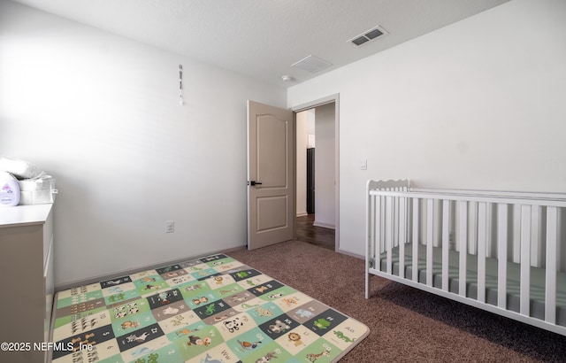 carpeted bedroom featuring a nursery area and a textured ceiling