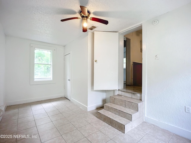 stairs with tile patterned flooring, ceiling fan, and a textured ceiling