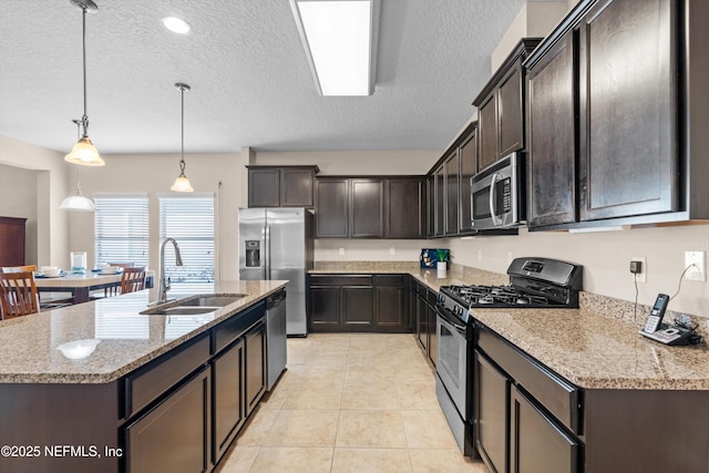 kitchen featuring sink, dark brown cabinets, pendant lighting, stainless steel appliances, and a kitchen island with sink