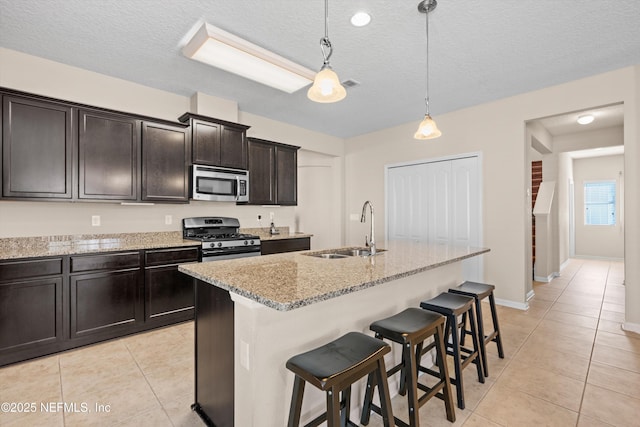 kitchen featuring pendant lighting, sink, a kitchen island with sink, light tile patterned floors, and stainless steel appliances