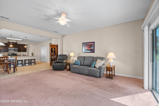 living room featuring light carpet, a textured ceiling, and ceiling fan