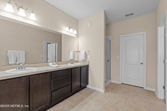 bathroom with vanity, tile patterned floors, an enclosed shower, and a textured ceiling