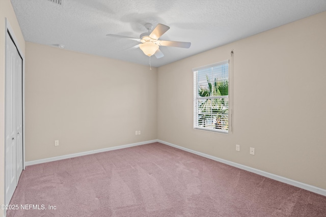 spare room featuring a textured ceiling, light colored carpet, and ceiling fan