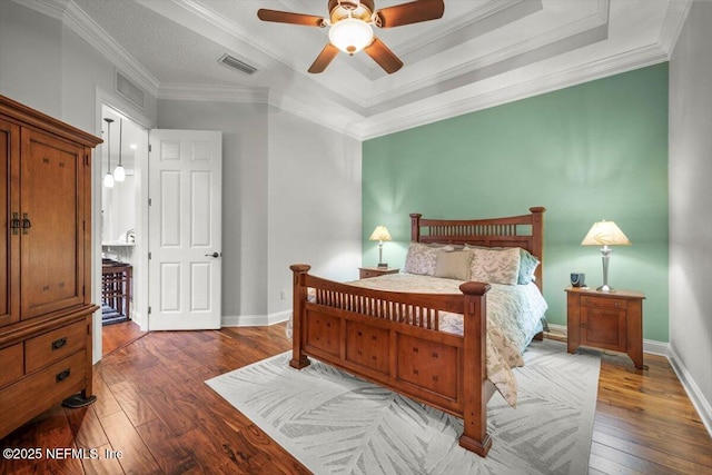 bedroom featuring dark hardwood / wood-style flooring, ornamental molding, and a raised ceiling