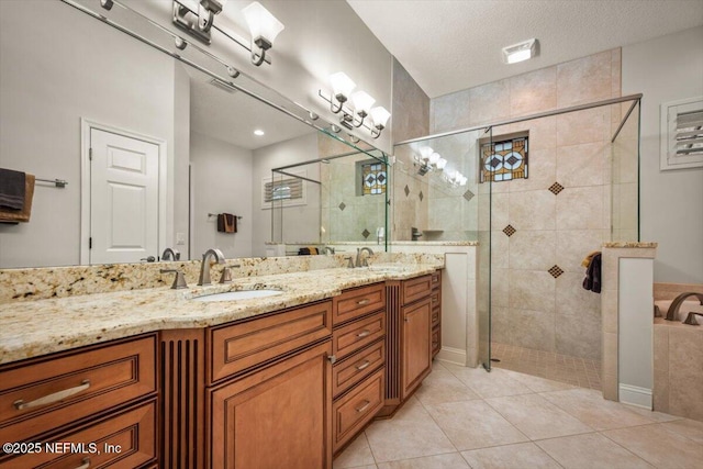 bathroom featuring vanity, a tile shower, tile patterned floors, and a textured ceiling