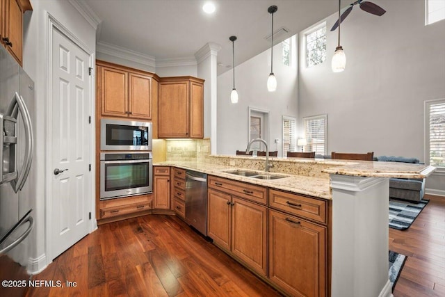 kitchen featuring decorative light fixtures, appliances with stainless steel finishes, sink, and kitchen peninsula