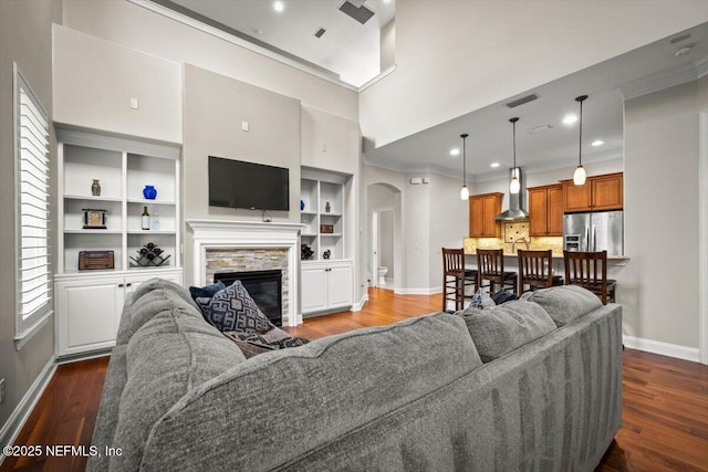 living room featuring a high ceiling, crown molding, dark hardwood / wood-style floors, and a fireplace