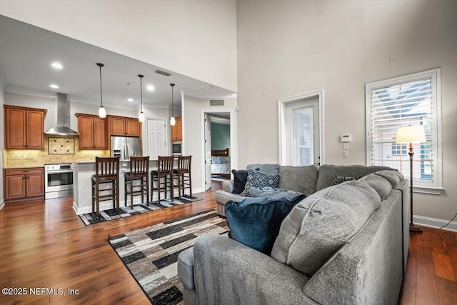 living room featuring crown molding, dark hardwood / wood-style floors, and a high ceiling