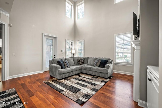 living room with a high ceiling, dark wood-type flooring, and a wealth of natural light