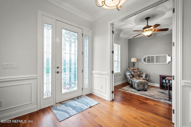 entryway with crown molding, ceiling fan, and light wood-type flooring