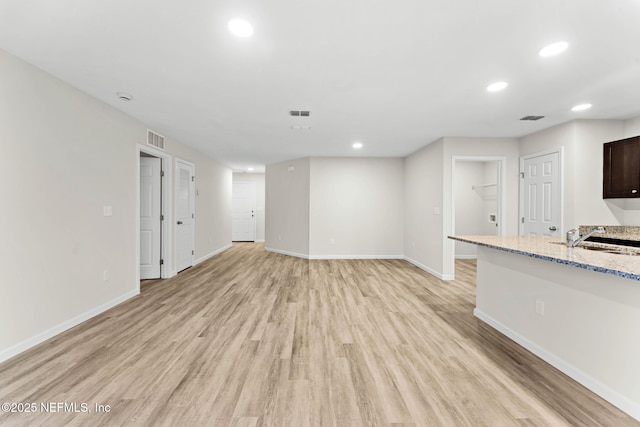 unfurnished living room featuring sink and light hardwood / wood-style flooring