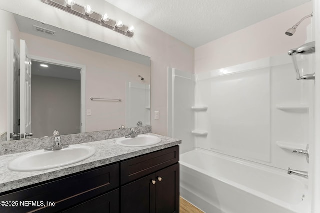 bathroom featuring vanity, bathing tub / shower combination, and a textured ceiling