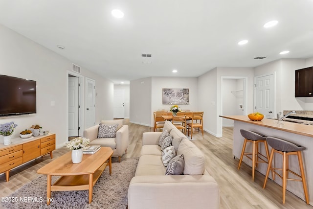 living room with sink and light hardwood / wood-style flooring