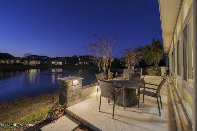 patio terrace at dusk featuring a water view