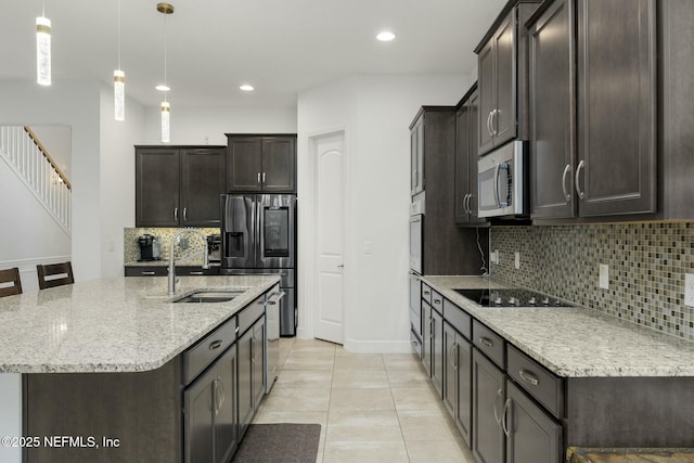 kitchen with sink, hanging light fixtures, light tile patterned floors, appliances with stainless steel finishes, and light stone countertops