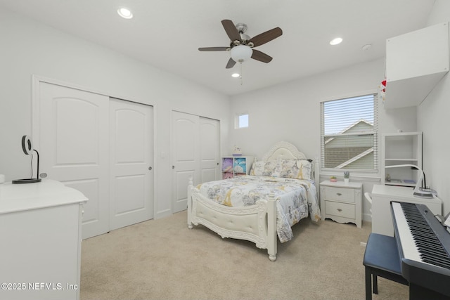 carpeted bedroom featuring multiple closets and ceiling fan