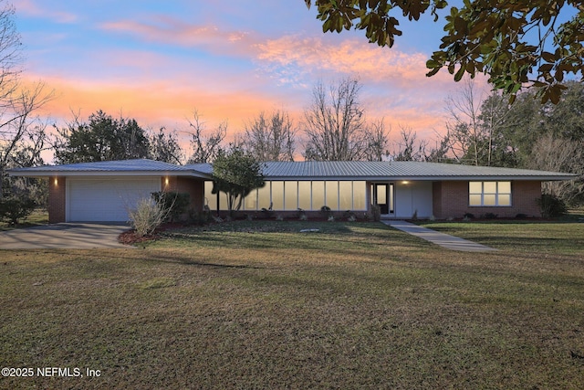 ranch-style home featuring a garage and a lawn