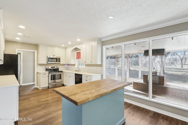 kitchen featuring sink, stainless steel appliances, a center island, white cabinets, and wood counters