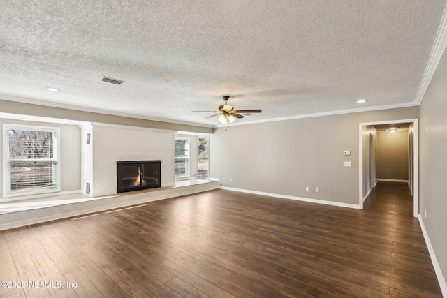 unfurnished living room with ornamental molding, dark hardwood / wood-style floors, a textured ceiling, and a fireplace