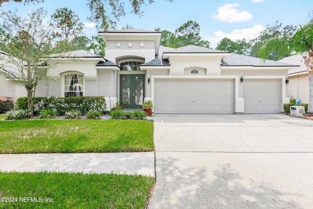 view of front of property with a garage, a front yard, and french doors