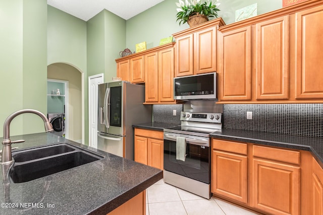 kitchen featuring light tile patterned flooring, appliances with stainless steel finishes, sink, and backsplash