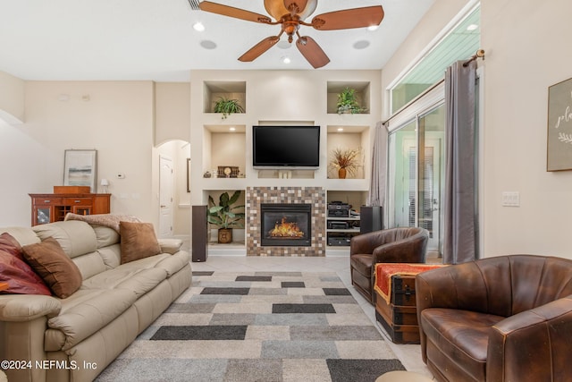 living room with a tiled fireplace and ceiling fan