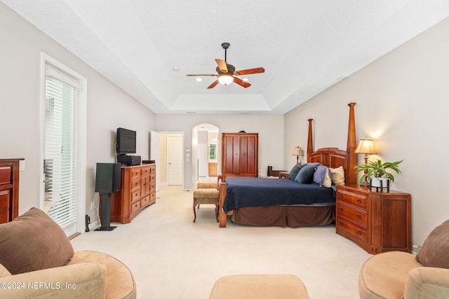 carpeted bedroom featuring a raised ceiling and ceiling fan