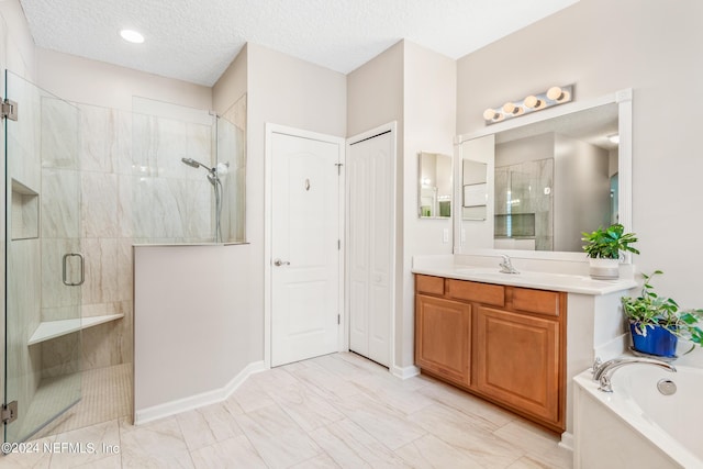 bathroom with vanity, a textured ceiling, and separate shower and tub