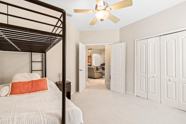 carpeted bedroom featuring ceiling fan, a closet, and a textured ceiling